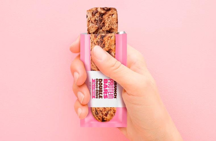 pink protein bar wrapper open to show bar product in hand